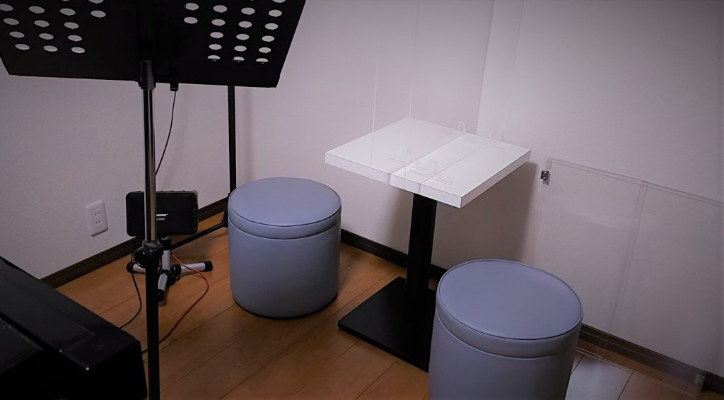 スタジオアマンドール内の設備：テーブル、いす、感染防止用アクリル板およびモニタースピーカー