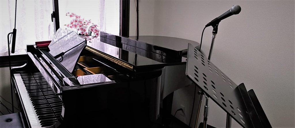 スタジオアマンドール内の設備：グランドピアノ、マイクロフォンスタンドと譜面台
